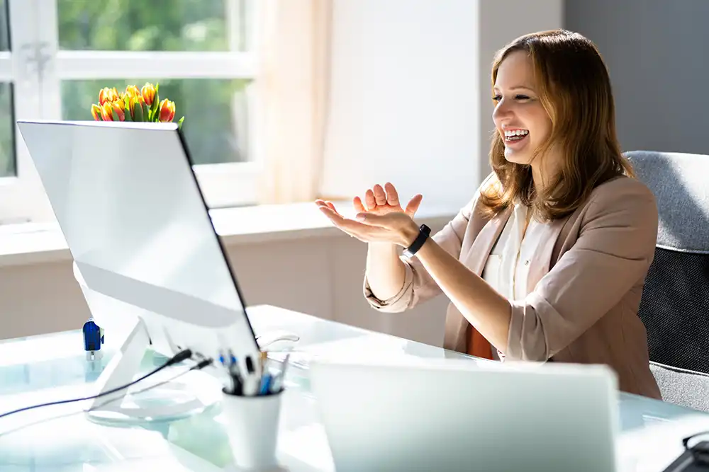 Woman sitting at office desk with computer during remote virtual business team meeting